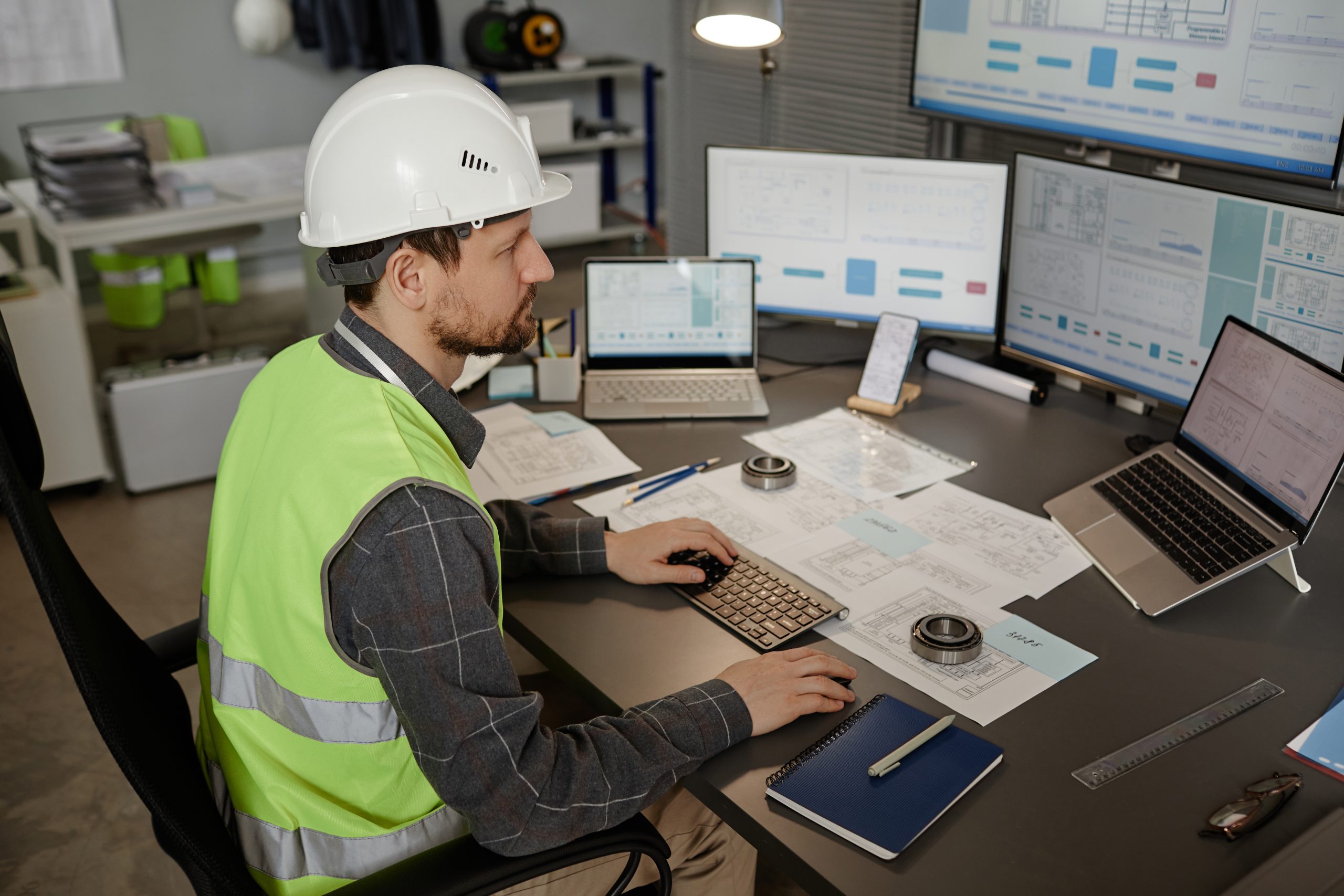 Engineer wearing hardhat at workplace in office and using computer informe_aceptacion_y_rechazo_calibracion